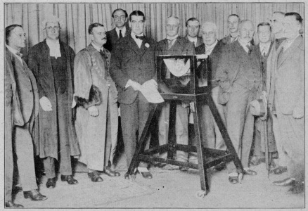 opening of 5xx daventry: H.M. Postmaster-General, Sir Wm. Mitchell-Thomson, Bt., K.B.E., M.P., standing before the microphone in the studio at Daventry. With him are: The Mayor of Daventry, Councillor J. H. Johnson (in robes); Mr. J. C. W. Reith (Managing Director); Lord Gainford (Chairman); Sir Wm. Bull at the right of the microphone and Mr. Litt, Engineer-in-Charge, on the extreme right. men standing in front of microphone